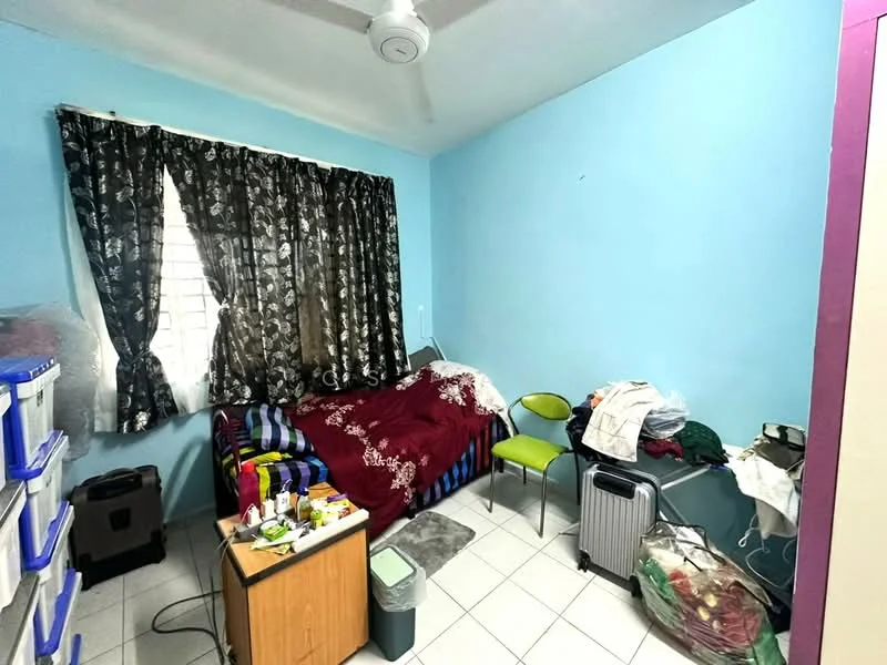 Bedroom features: light blue painted walls, white ceiling, black floral patterned curtains, single bed with maroon bedding, green chair, wooden bedside table, plastic storage boxes, tiled flooring, ceiling fan.