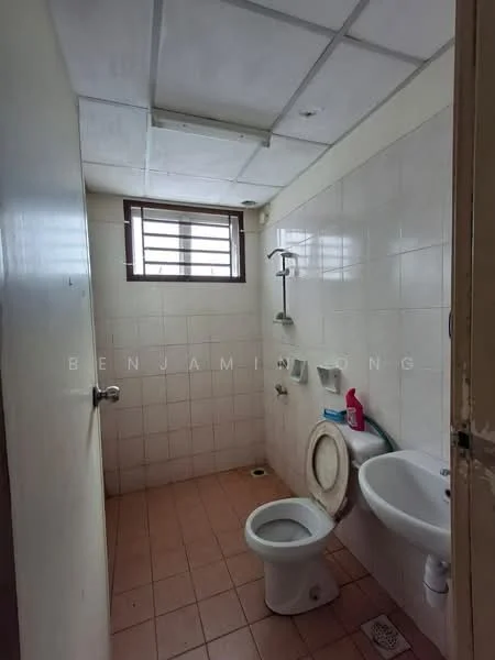 Bathroom features: white tiled walls, brown tiled flooring, toilet, sink with faucet, shower head, window with metal grille, wall-mounted soap holder, toilet paper holder.