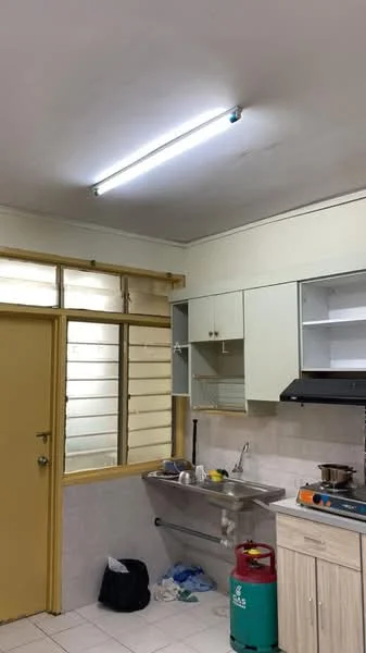 Kitchen features: white painted walls, light grey cabinetry, stainless-steel sink, chrome faucet, tile backsplash, white tile flooring, overhead fluorescent lighting, window with horizontal slats, kitchen countertop, gas stove, green gas cylinder.