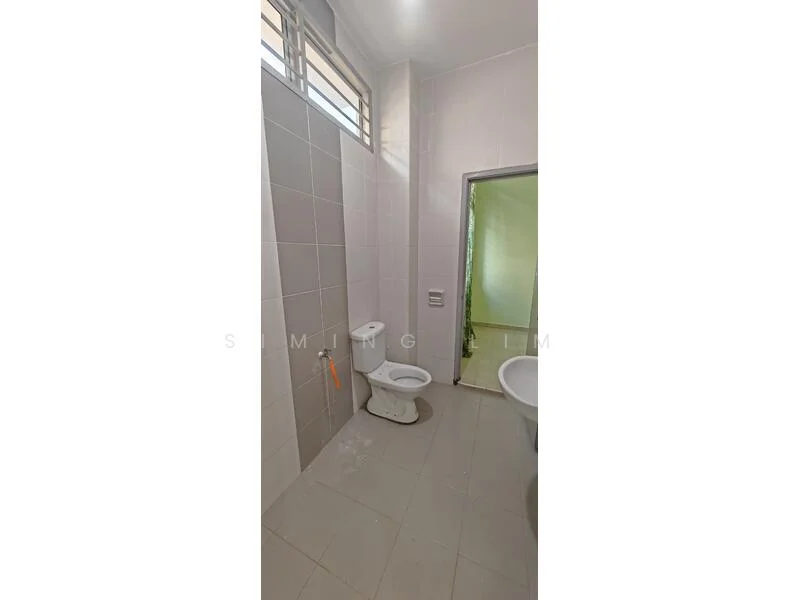 Bathroom features: white toilet, grey tiled walls, light grey floor tiles, window for natural light, shower area, sink area, chrome towel rail, basic lighting.