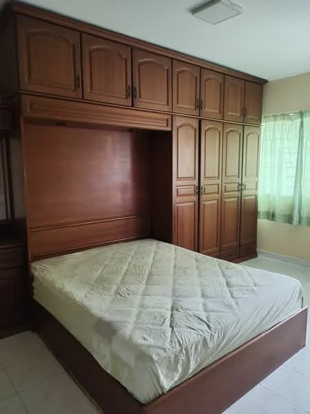 Bedroom features: queen-size bed, wooden bed frame, built-in wooden wardrobe with multiple doors, light green curtains, white tiled flooring, ceiling light fixture, neutral wall color, mattress with beige cover; style: traditional.