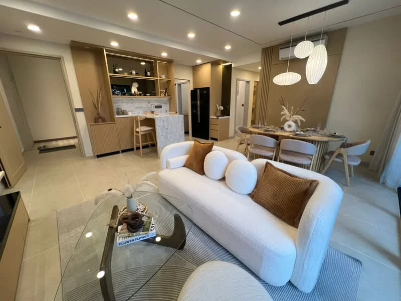 Living features: white fabric sofa with round cushions, glass coffee table, area rug with geometric pattern, recessed downlights, wall-mounted TV, decorative vase with dried plants, open shelving with decorative items, marble countertop at kitchen island, dining table with wooden chairs, kitchen cabinetry in light wood, floor-to-ceiling windows with sheer curtains, neutral wall color, tile flooring; style: modern.