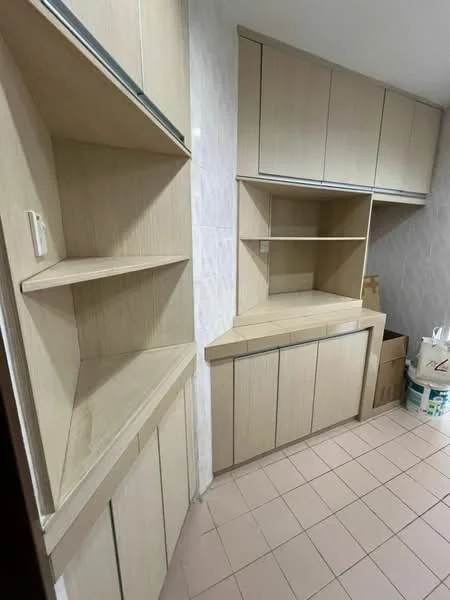Room features: built-in cabinetry with light wood finish, open shelving, closed cabinets, countertop surface, tile flooring in light color, wall with light-colored tile cladding, storage boxes visible, corner shelving unit; style: modern.