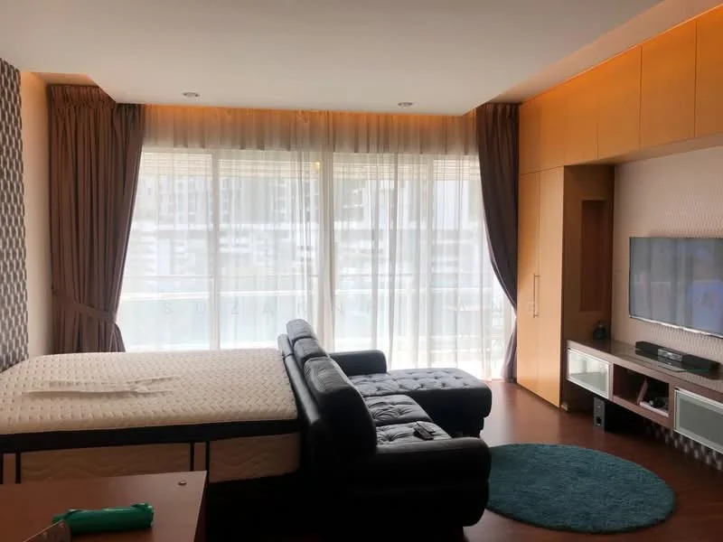 Living features: floor-to-ceiling windows, sheer curtains, dark brown leather sectional sofa, wooden flooring, built-in TV console, wall-mounted TV, decorative wall paneling, area rug with circular shape, recessed lighting, light wood cabinetry, green accent decor item; style: modern; view: city.