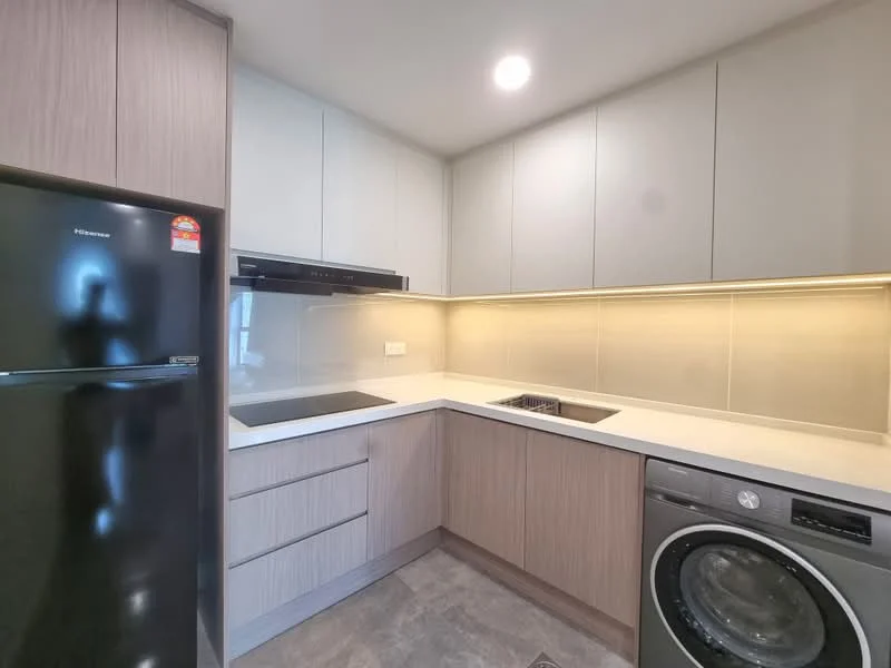 Kitchen features: grey cabinetry, light wood cabinetry, white countertop, built-in oven, stainless-steel sink, chrome pull-down faucet, black refrigerator, built-in cooktop, washer-dryer combo, tile backsplash, recessed LED downlights, grey tile flooring; style: modern.