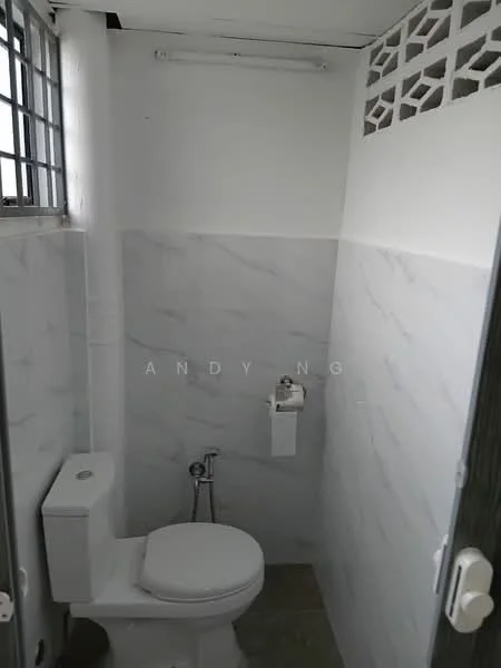 Bathroom features: white ceramic toilet, chrome toilet paper holder, white wall tiles with marble pattern, grey floor tiles, window with metal grille, ceiling light fixture, exposed plumbing, wall-mounted bidet spray; style: modern.