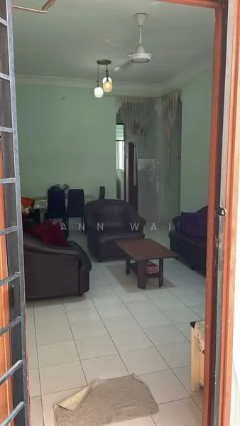 Living features: white painted walls, ceramic tile flooring, 5-blade ceiling fan with light, 3-seater leather sofa in dark brown, 2-seater leather sofa in dark brown, wood coffee table, area rug, dining table with chairs in background, refrigerator visible in background.