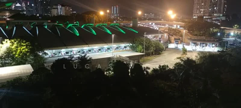 Exterior features: night view with illuminated structures, green lighting on roof, open-air parking area, surrounding greenery, adjacent highway, urban skyline in background; style: modern.