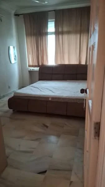 Bedroom features: king-size bed, upholstered headboard, brown bed frame, marble flooring, floor-to-ceiling window, sheer curtains, wall-mounted mirror, decorative wall paneling, light fixture on ceiling; style: modern.