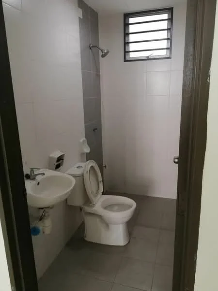 Bathroom features: white ceramic toilet, single-sink vanity with chrome faucet, shower with wall-mounted shower head, grey wall tiles, white floor tiles, window with horizontal bars, toilet paper holder, soap dispenser.