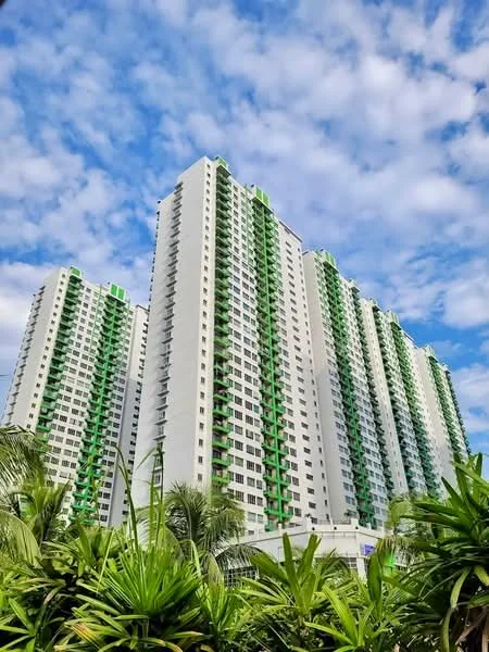 Exterior type: high-rise condominium; features: white painted facade, green accent balconies, approximately 20-storey high-rise, tropical landscaping with palm trees, manicured shrubs, clear blue sky, clouds in the background; style: modern.