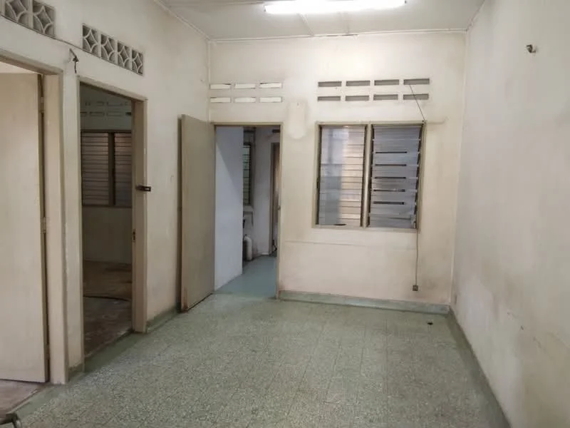 Room features: plain white walls, green vinyl flooring, sliding windows with horizontal slats, two doorways leading to other rooms, ceiling lights, no visible furniture, minimal decor, neutral color scheme; style: traditional.