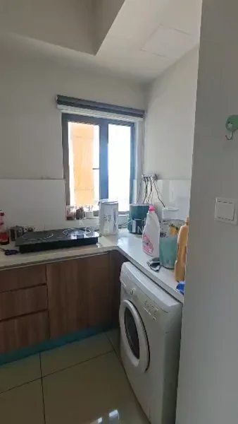 Kitchen features: wood cabinetry, white countertops, single-bowl stainless-steel sink, chrome pull-down faucet, built-in gas hob, front-load washing machine, window with view, tile flooring, recessed ceiling lights, kitchen appliances, cleaning supplies on countertop; style: modern; view: city.