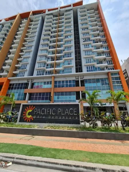 Exterior type: high-rise condominium; features: glass curtain wall, orange and grey facade, recessed balconies, multiple storeys, signage at the base, manicured landscaping, paved walkway, surrounded by palm trees; style: modern.