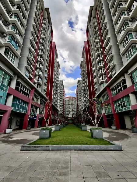 Exterior type: mid-rise condominium; features: red and grey facade, multiple storeys, landscaped garden area, paved walkway, planters with trees, large windows, balconies on upper floors, symmetrical building layout; style: modern.
