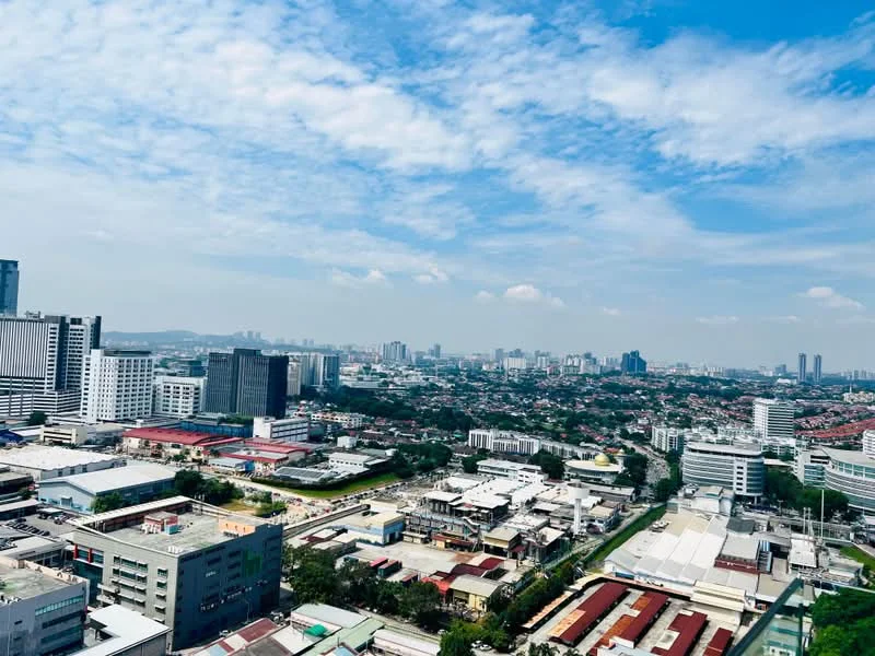 Exterior type: high-rise condominium; features: city skyline view, surrounded by urban landscape, visible commercial buildings, residential areas in the foreground, clear blue sky, scattered clouds; style: modern.