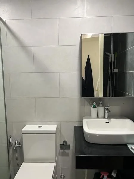 Bathroom features: white wall tiles, grey accent wall tiles, single-sink vanity with black countertop, oval sink, chrome basin mixer faucet, framed mirror, one-piece toilet, shower with glass enclosure, towel rack, toiletries on countertop; style: modern.