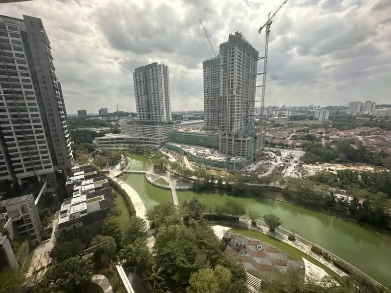 Exterior type: high-rise condominium; features: glass curtain wall, surrounded by greenery, waterfront view, construction site visible, urban skyline in background, landscaped pathways, park area with seating, multiple high-rise buildings, manicured lawns; style: modern.