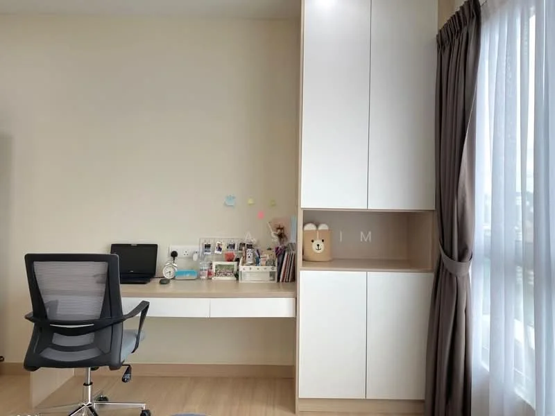 Study features: light wood flooring, white painted walls, built-in white cabinetry, desk with storage, black office chair, decorative items on desk, window with sheer curtains, natural light from window; style: modern.
