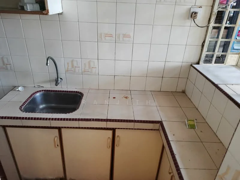 Kitchen features: single-bowl stainless-steel sink, chrome faucet, white tiled backsplash, cream cabinetry, countertop with tiled surface, visible stains on countertop, built-in countertop area, wall-mounted electrical outlet.