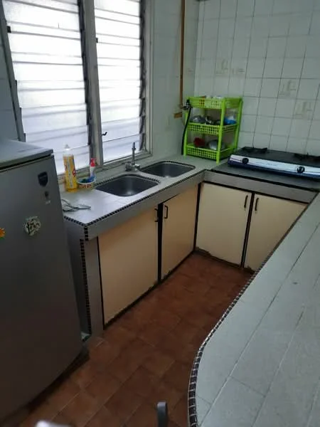 Kitchen features: double-bowl stainless-steel sink, chrome pull-down faucet, grey countertop, cream cabinetry with black handles, built-in gas stove, stainless-steel fridge, tile backsplash, brown tiled flooring, window with horizontal slats, open shelving unit, cleaning supplies on countertop.