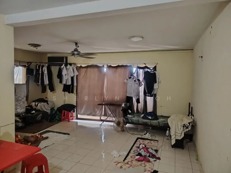 Room features: white painted walls, tiled flooring, ceiling fan, floor-to-ceiling windows, curtains, clothes hanging on a rack, folding table, sofa, scattered clothing on the floor, plastic chairs.