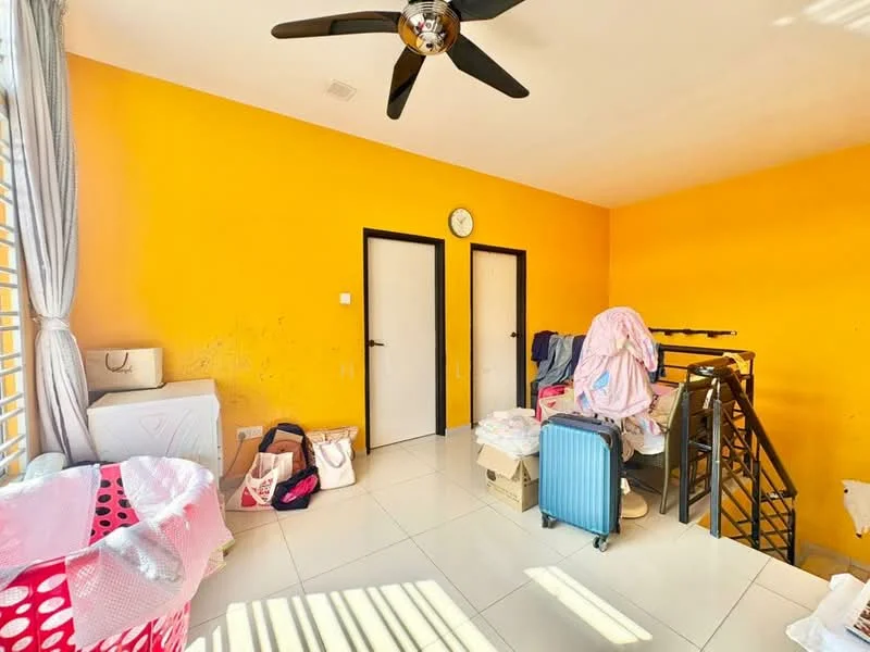 Room features: yellow painted walls, white tiled flooring, 5-blade ceiling fan, two doors, window with blinds, laundry basket, stack of bags, blue suitcase, bedding items, metal staircase.