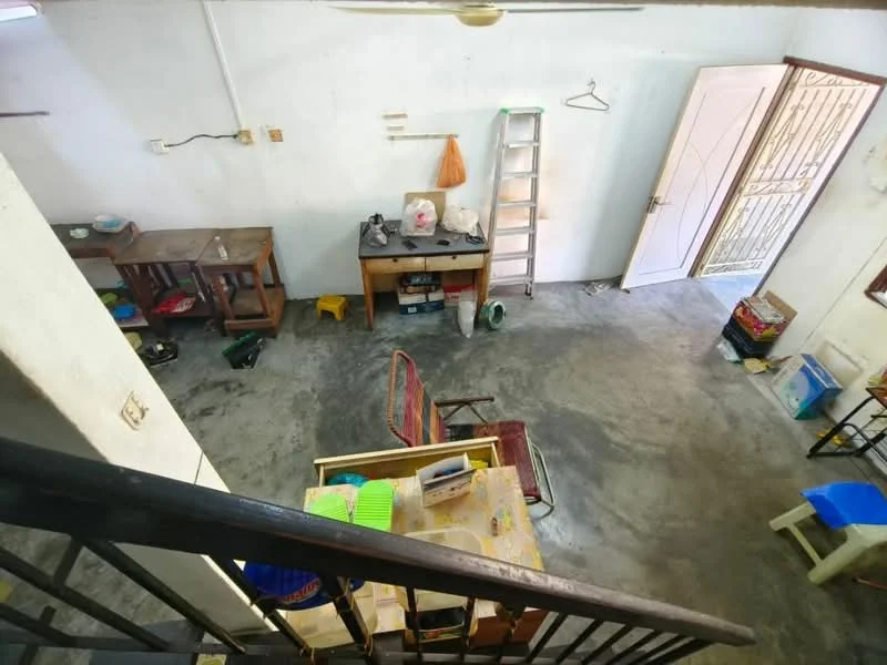 Room features: concrete flooring, white painted walls, ceiling fan, wooden dining table, wooden chairs, metal ladder, open doorway, shelves, plastic storage containers, various household items; style: minimalist.