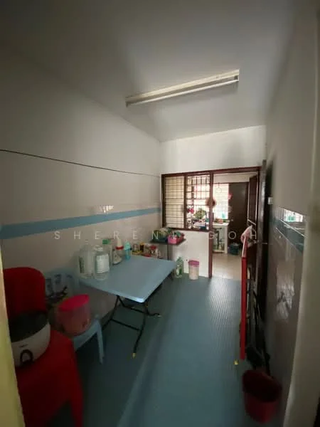 Room features: blue vinyl flooring, white painted walls, wooden door, glass sliding door, table with plastic chairs, rice cooker, plastic storage containers, shelves with various items, refrigerator, sink, window with grid pattern.