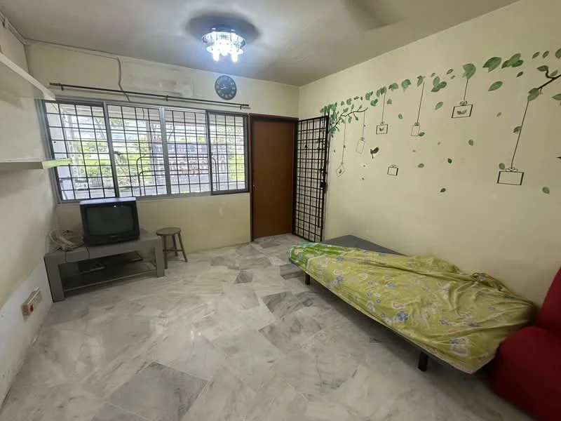 Living features: marble flooring, white painted walls, ceiling light fixture, window with metal grille, TV console, television, single bed with bedding, red armchair, decorative wall decals, wooden door, stool.