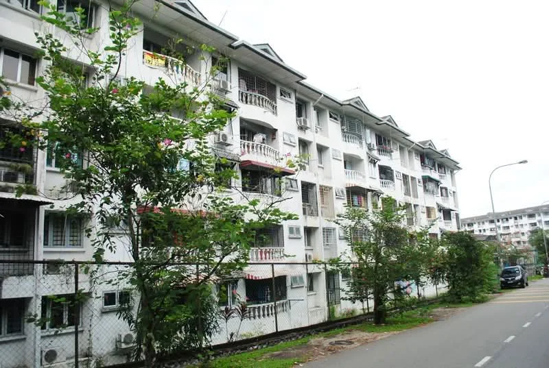 Exterior type: low-rise apartment block; features: white painted facade, recessed balconies, multiple windows, green landscaping with trees, fenced perimeter, street view, parking area visible, two-storey building, asphalt road; style: modern.