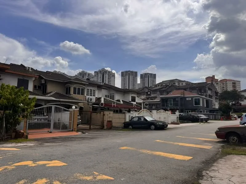 Exterior type: linked terrace house; features: two-storey linked terrace houses, white painted facade, driveway with interlocking pavers, manicured lawn, surrounded by mature greenery, urban context with high-rise buildings in background, open-air parking lot, guard house at entrance; style: modern.