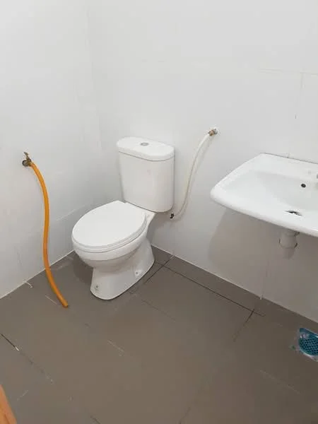 Bathroom features: white toilet, white sink, grey tiled flooring, white tiled walls, exposed plumbing, single faucet, no visible storage, no mirror.
