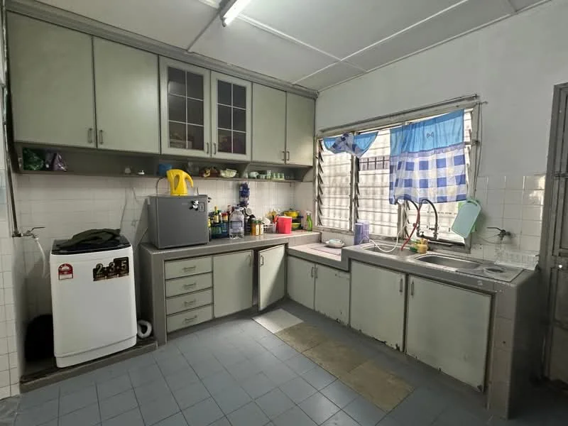 Kitchen features: grey cabinetry with glass-front upper cabinets, double-bowl stainless-steel sink, chrome pull-down faucet, white tiled backsplash, white tiled walls, grey tiled flooring, freestanding washing machine, refrigerator, window with blue checkered curtain, countertop space, kitchen utensils and bottles on countertop.