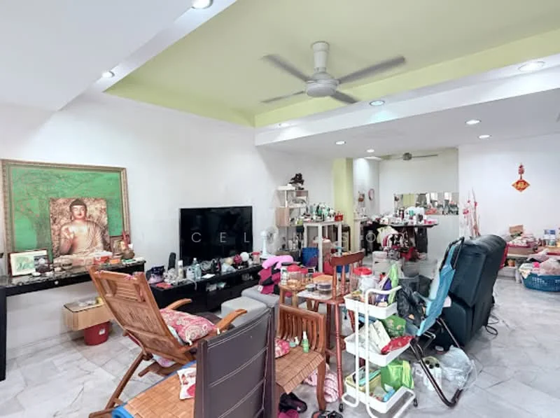 Living features: white painted walls, marble tile flooring, tray ceiling with recessed lighting, 5-blade ceiling fan, large flat-screen TV, wooden coffee table, multiple decorative items, various furniture pieces including chairs and shelves, cluttered space with personal items.