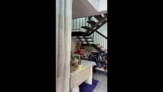 Living features: staircase with wooden steps and metal railing, sofa with colorful upholstery, coffee table with lace tablecloth, decorative flowers in vase, purple area rug, white walls, marble flooring, curtain separating spaces; style: modern.