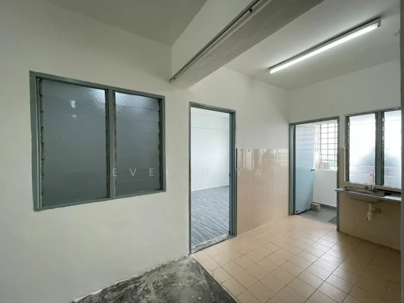 Room features: white painted walls, grey tiled flooring, two windows with metal frames, doorway leading to another room, kitchen area with tiled backsplash, fluorescent ceiling lights.