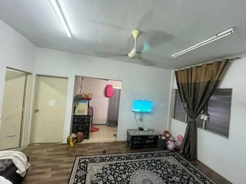 Living features: laminate flooring, white painted walls, ceiling fan, wall-mounted TV, coffee table, sofa, area rug with geometric pattern, curtains, window with blinds. Room features: door leading to another room, kitchenette area visible, tiles on floor, open doorway, storage cabinets.