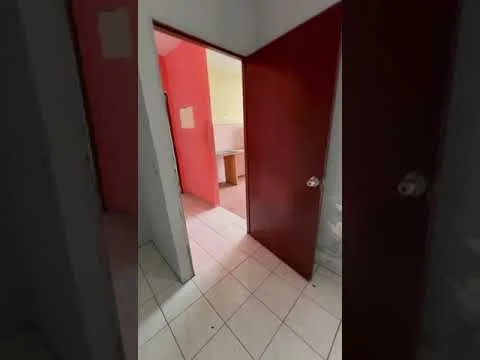 Room features: white walls, pink accent wall, tile flooring, wooden door, door frame, light switch, visible doorway to another room.