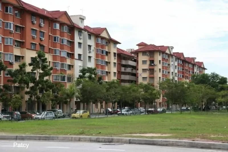 Exterior type: low-rise apartment block; features: red and cream painted facade, flat roof, approximately 4-storey high-rise, balconies on upper floors, manicured lawn in front, surrounded by trees, parking spaces visible, street view; style: modern.