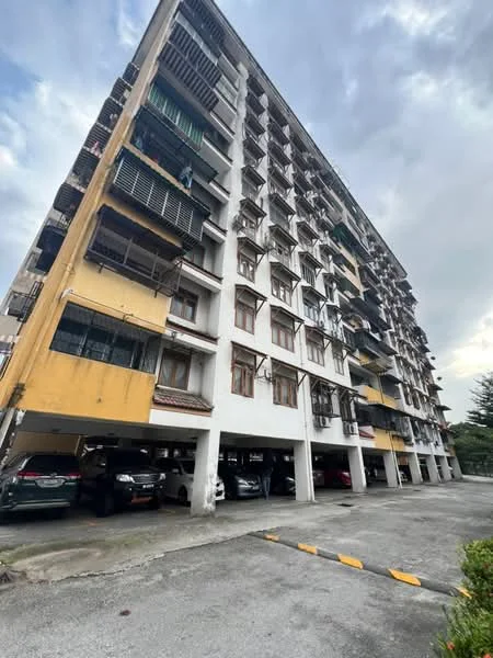 Exterior type: low-rise apartment block; features: exposed concrete facade, yellow painted facade, balconies with metal railings, ground-level parking area, multiple storeys, windows with wooden frames, overhangs for shading, surrounded by greenery; style: modern.