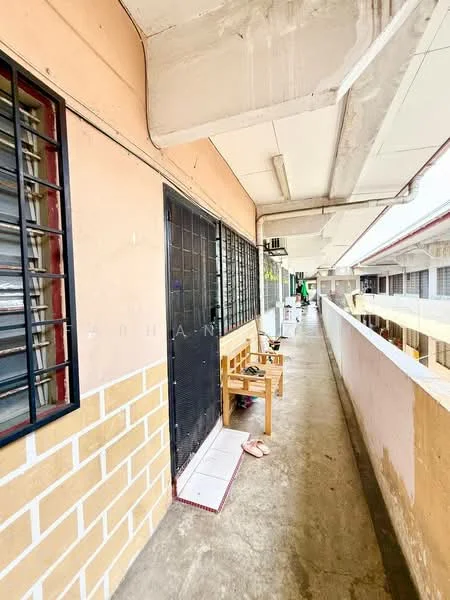 Exterior type: low-rise apartment block; features: concrete walkway, metal grilles on windows, light-colored painted facade, exposed concrete ceiling, wooden bench, tiled flooring, balcony railing, door with security grille; style: minimalist.