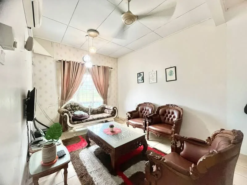 Living features: 3-seater fabric sofa in beige, 2-seater leather sofa in brown, wooden coffee table with intricate carvings, area rug with geometric pattern in red and white, wall-mounted TV, ceiling fan with light, curtains in beige, decorative wall art, white painted walls, tile flooring; style: traditional.
