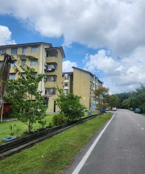 Exterior type: low-rise apartment block; features: yellow painted facade, 3-storey building, balconies with plants, manicured lawn, paved walkway, surrounded by greenery, roadside view, cloudy sky; style: modern.