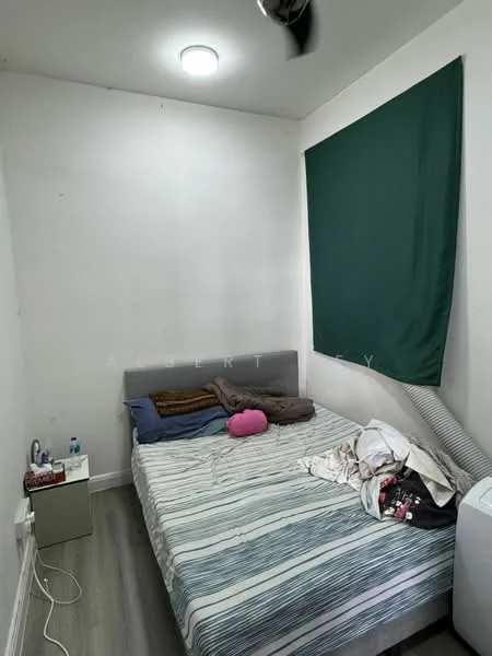 Bedroom features: queen-size bed with striped bedding, green curtain, white painted walls, laminate flooring, ceiling light fixture, wall-mounted fan, nightstand with water bottle, pile of clothes on bed, air conditioning unit.