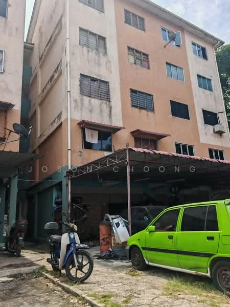Exterior type: low-rise apartment block; features: orange painted facade, multiple storeys, balconies with red awnings, visible windows with metal grilles, parking area with vehicles, exposed brick wall, satellite dishes mounted on walls, ground-level garage area; style: traditional.