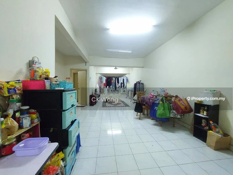 Room features: white painted walls, glossy white tile flooring, fluorescent ceiling lights, open layout, multiple doorways, clothes hanging on a rack, various storage containers, tables with items, kitchen items on shelves, plastic bags, baskets; style: minimalist.