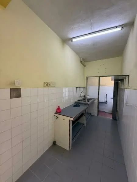 Kitchen features: yellow painted walls, white tiled backsplash, grey floor tiles, single-bowl stainless-steel sink, wall-mounted faucet, kitchen countertop, open shelving, cabinets below countertop, fluorescent ceiling lights.