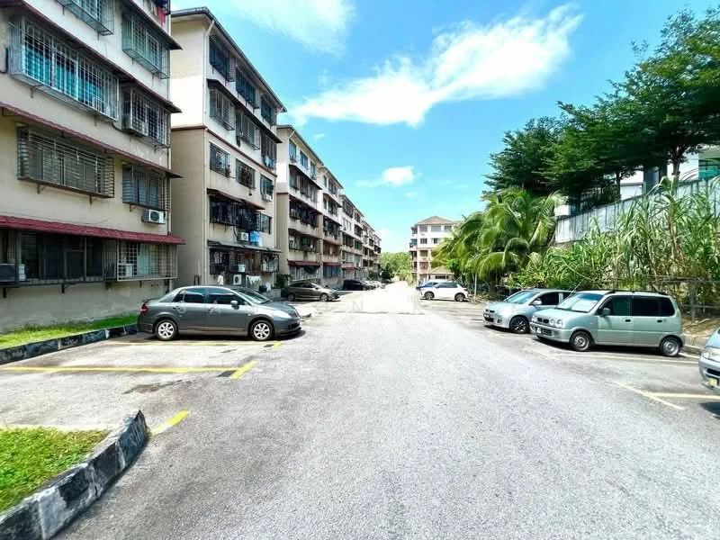 Exterior type: low-rise apartment block; features: multiple storey buildings, parking lot, landscaped greenery, paved driveway, balconies on upper floors, air conditioning units visible, surrounding trees, clear blue sky; style: modern.