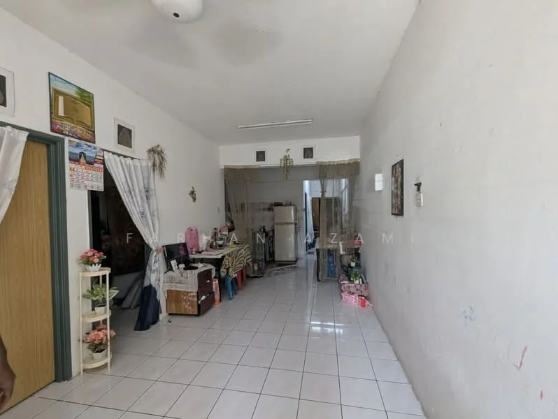 Room features: white painted walls, white tiled flooring, ceiling fan, wooden door, decorative wall hangings, open shelving unit, various decorative items, refrigerator, multiple bags and boxes, window with sheer curtains.